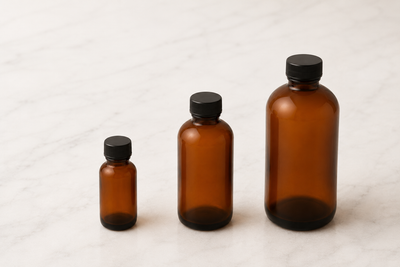 Three amber fragrance bottles with black caps on a light background
